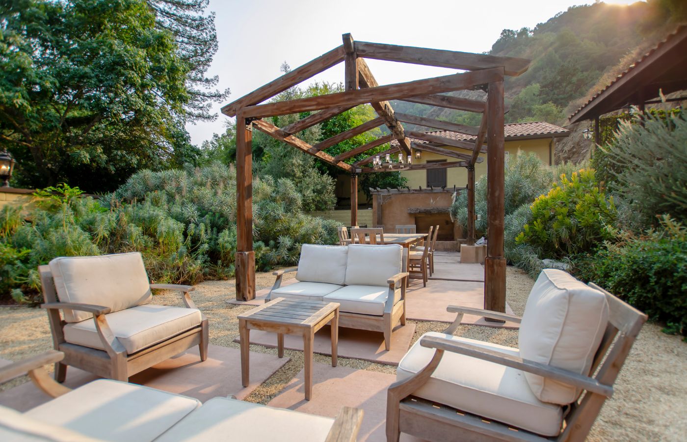 Cozy patio with cushioned seating under a wooden pergola.