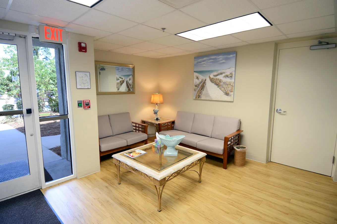 Waiting area with sofas, coffee table, lamp, and coastal wall art