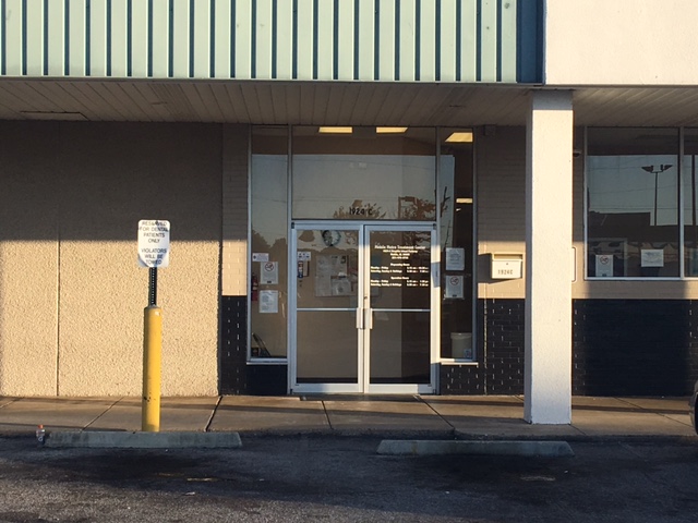The entrance of a treatment center with glass doors and posted notices.