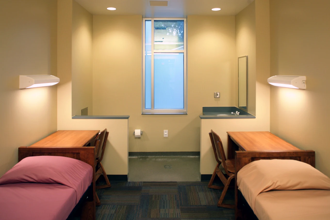 Shared bedroom with two single beds, desks, and a window