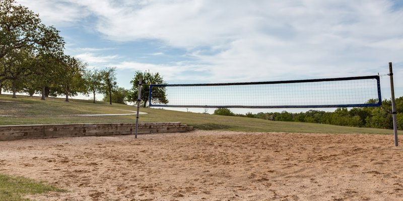  A sandy volleyball court set amidst rolling green hills, offering a perfect spot for outdoor fun and relaxation under the open sky.