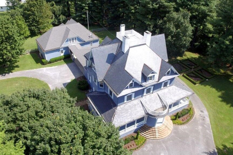 Aerial view of large blue house with circular entry steps
