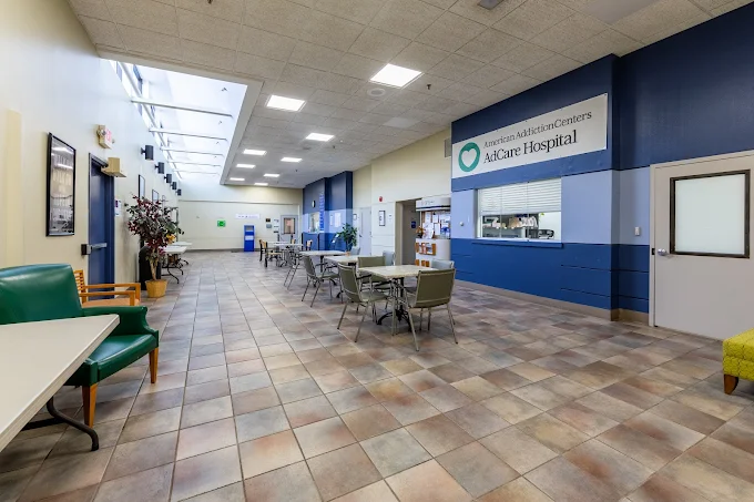 Spacious lobby with tables, seating, and AdCare Hospital signage