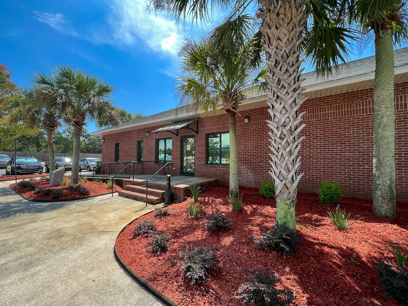 Brick facility entrance with palm trees and parking lot