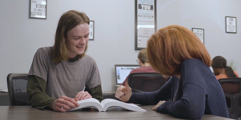  A student and tutor share a moment of laughter while working together, creating a positive and encouraging learning environment.