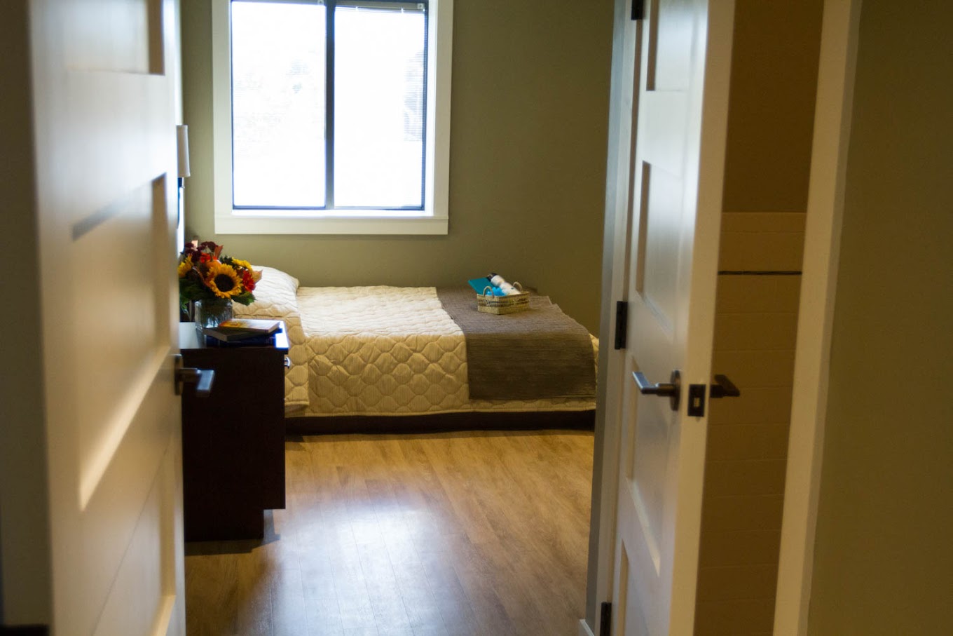 Single bed with flowers beside a large window