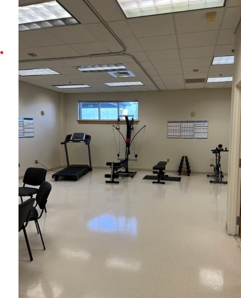 Small fitness room with a treadmill, multi-function machine, stationary bike, and weights