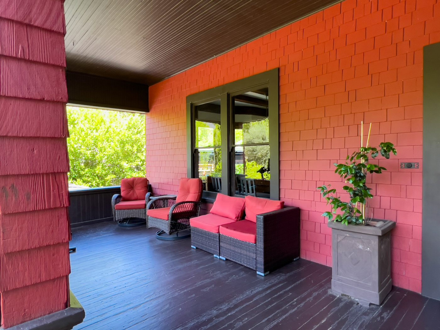 Covered porch with cushioned chairs and potted plant