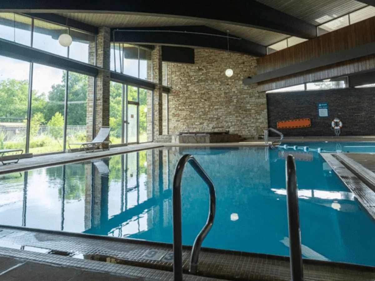 Indoor swimming pool surrounded by stone walls and windows