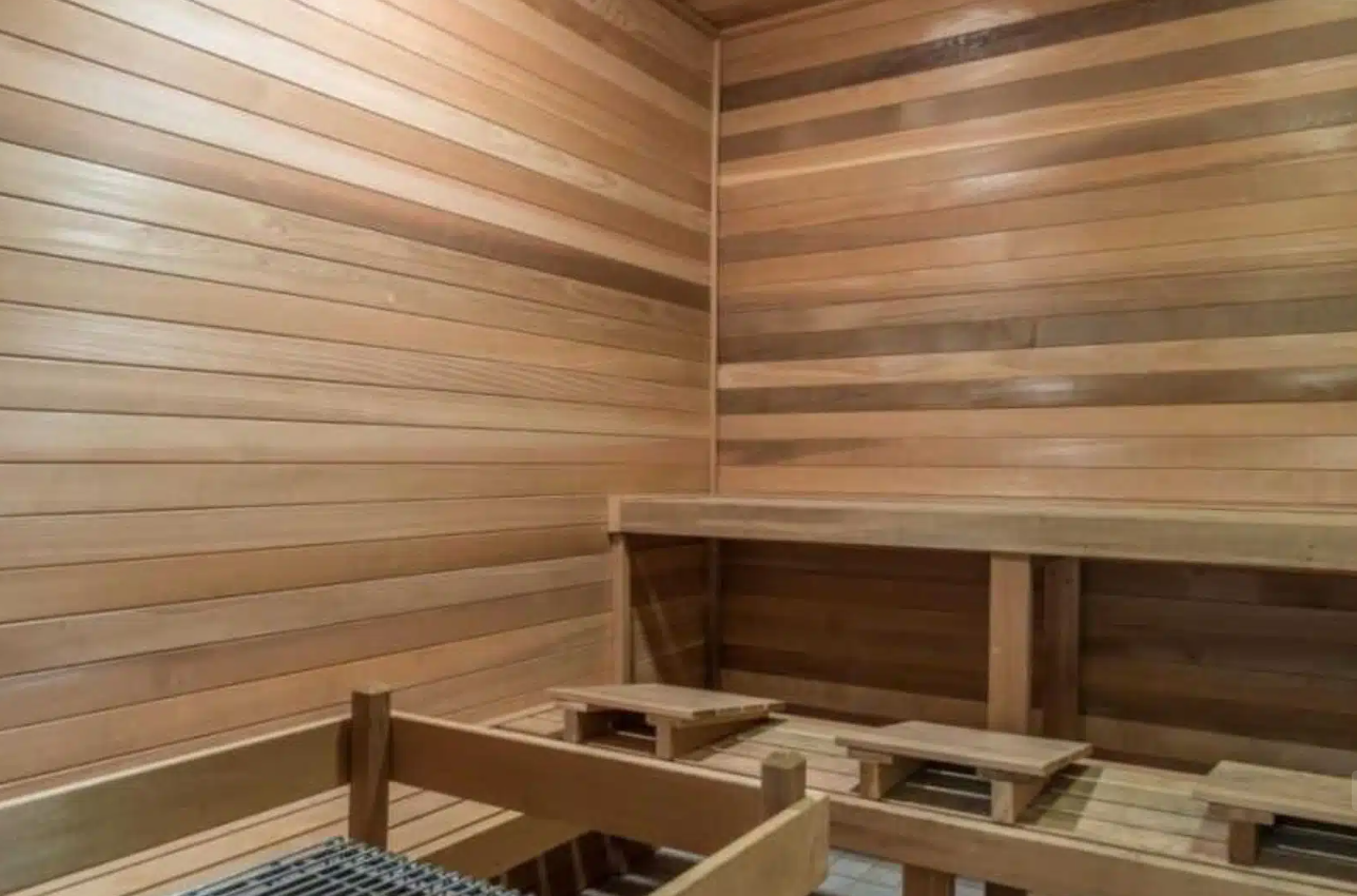 Wood-paneled sauna with tiered seating and heater