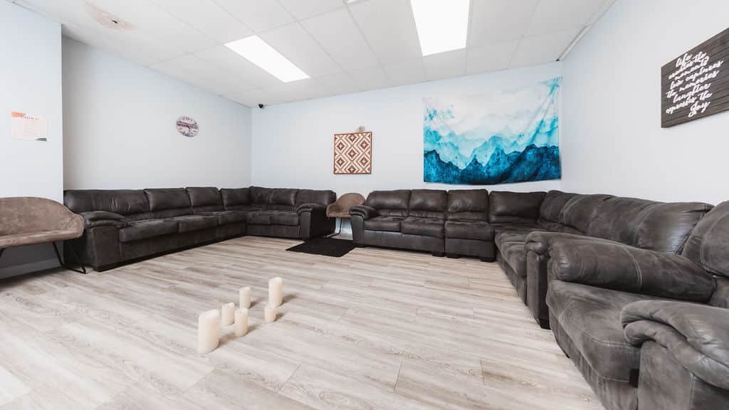 Spacious group therapy room with leather couches and wall art