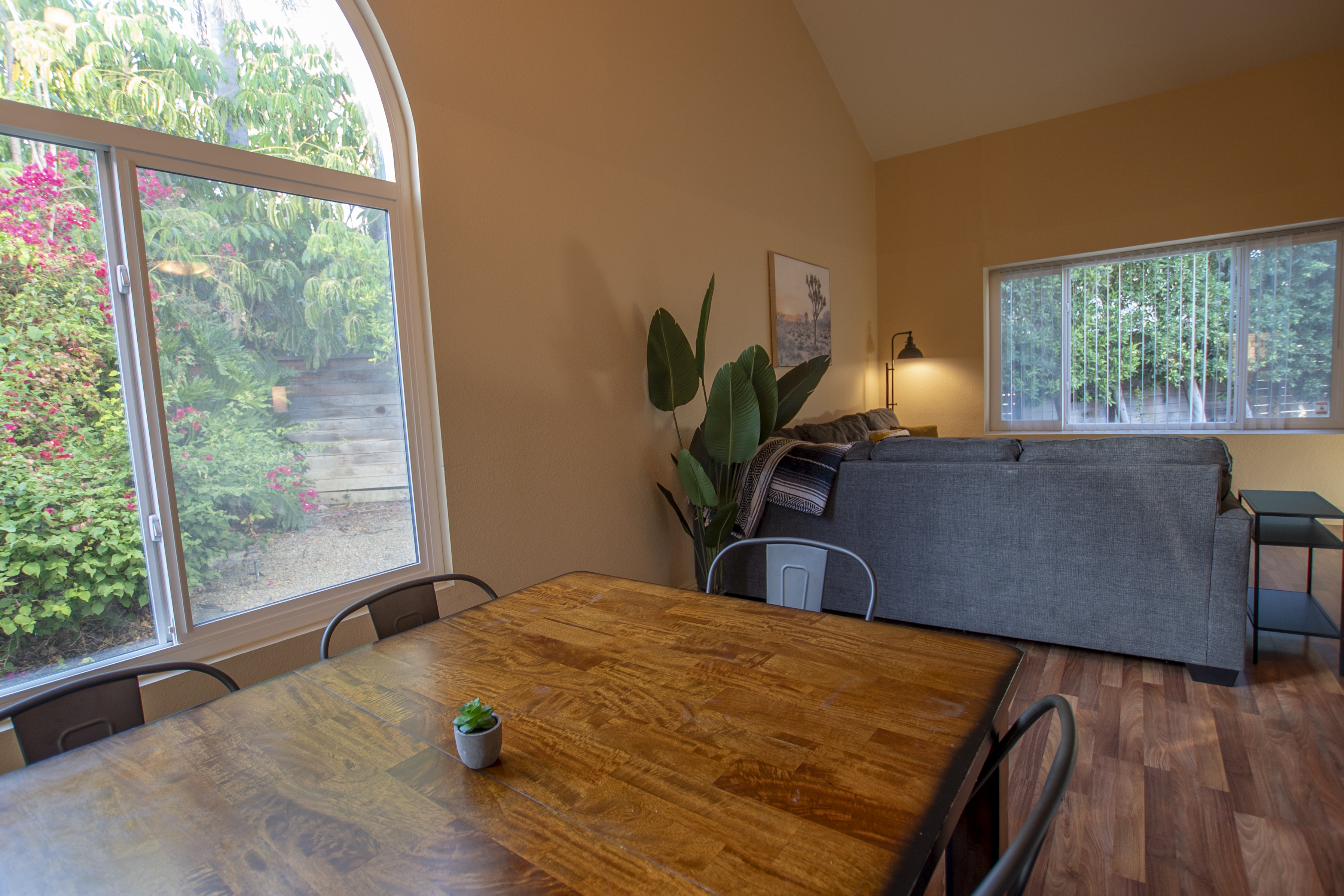 Wooden dining table by large window with greenery