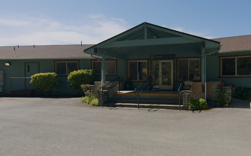 Facility entrance with covered porch and green siding