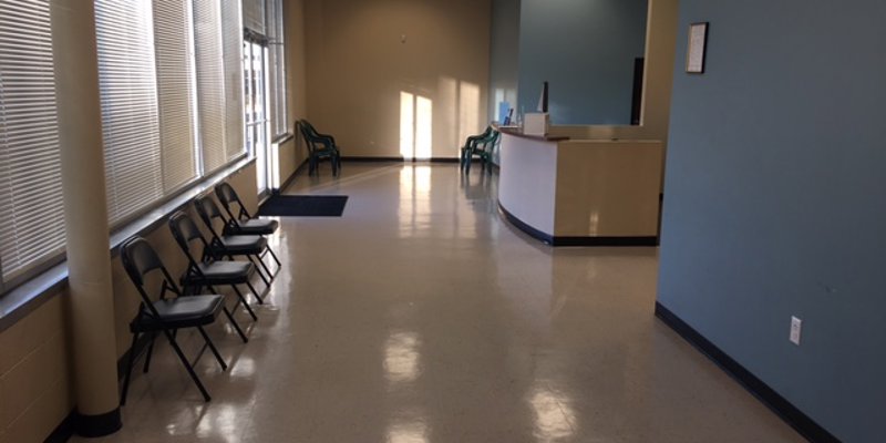 A spacious waiting area with large windows, chairs lined along the wall, and a welcoming front desk bathed in natural light.