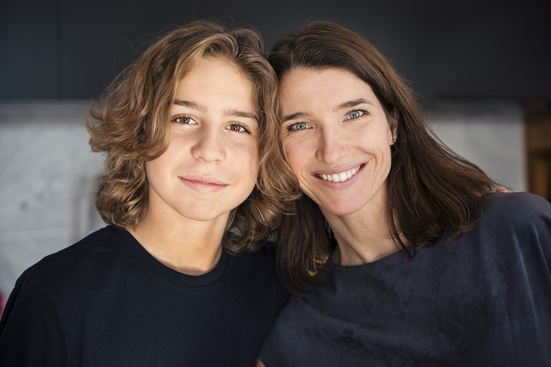 Mom and teen son smiling and standing close together.