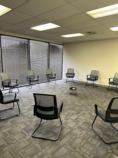 A group therapy room with chairs arranged in a circle near large windows.