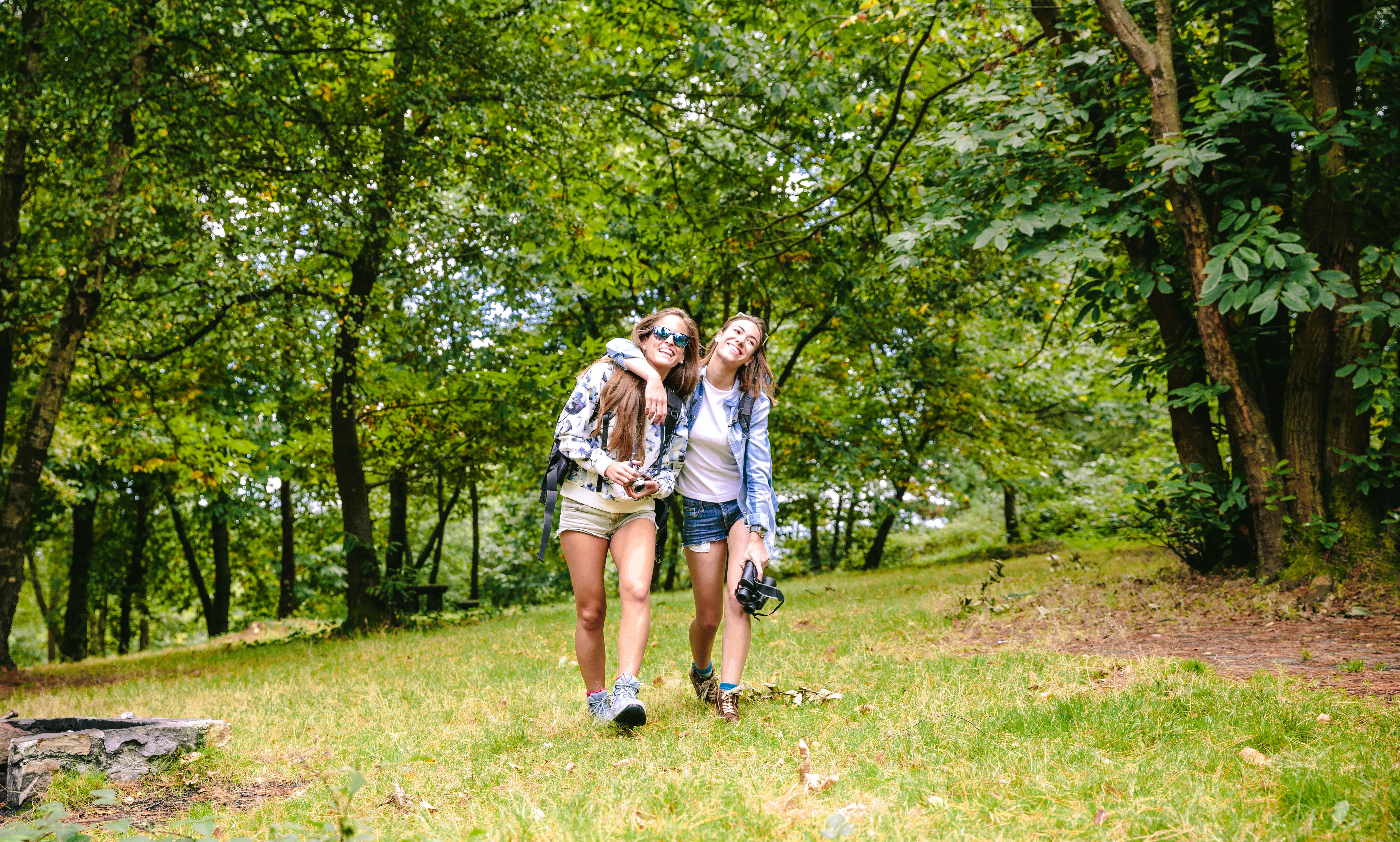 Two teens walking together on a forest trail.