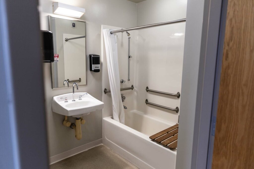 Bathroom with tub, grab bars, and wall-mounted sink
