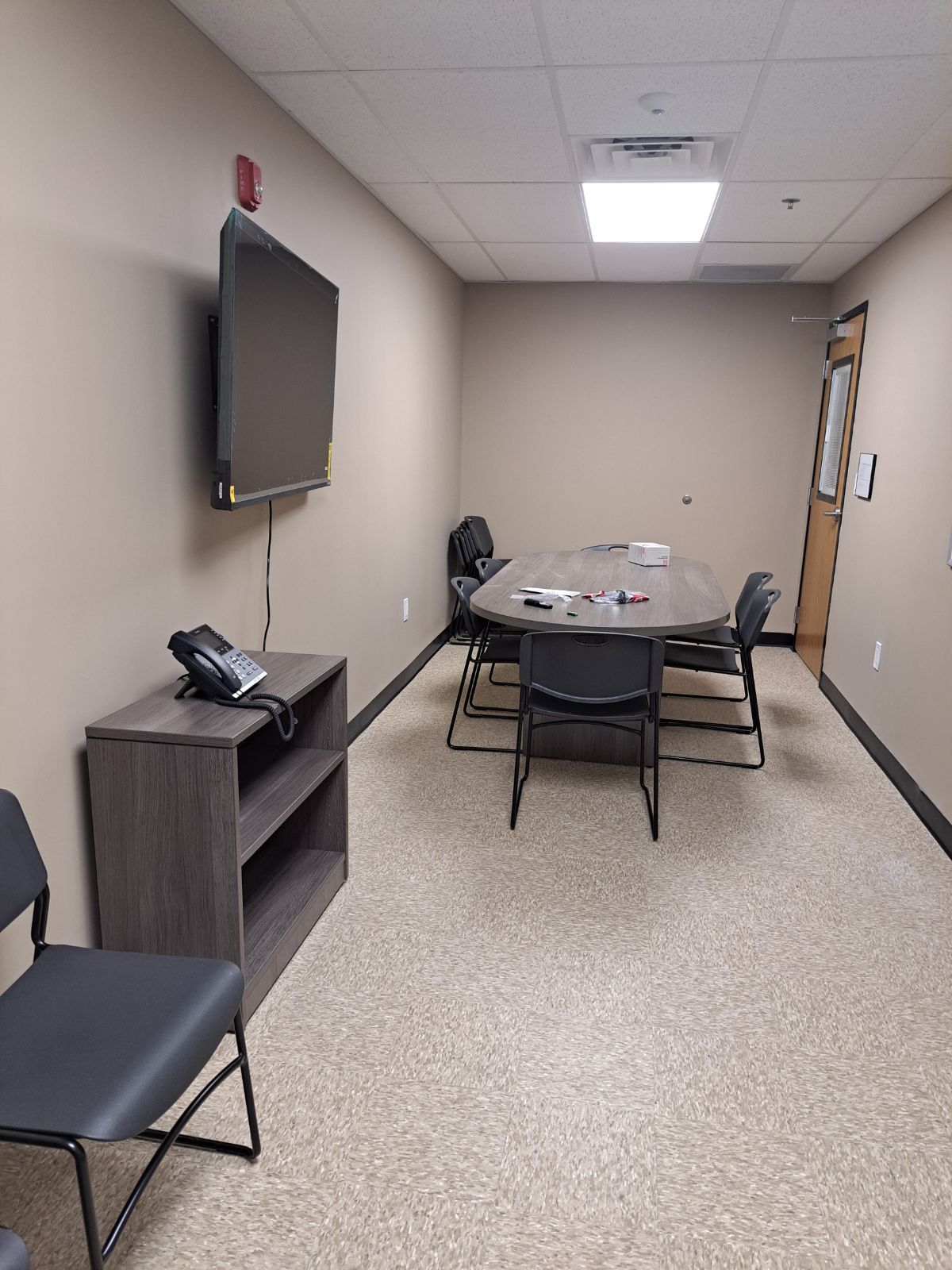 Group meeting room with table, chairs, and wall-mounted TV.