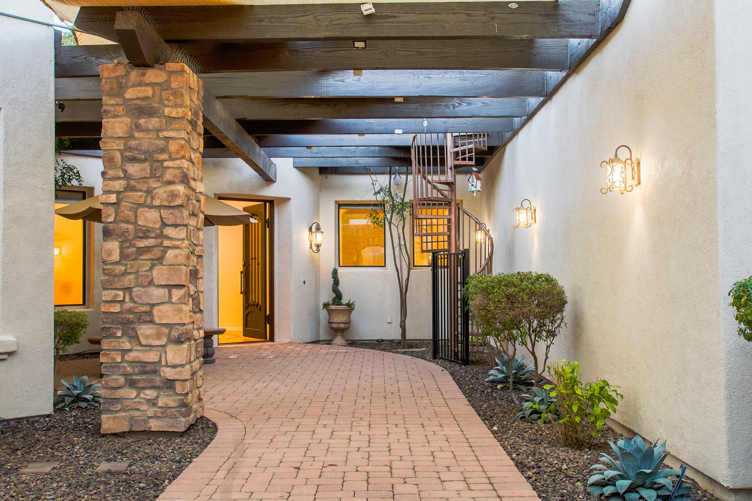 Covered courtyard walkway with stone columns and landscaping