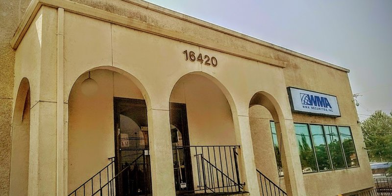 A welcoming, tan-colored building with arched entrances and large windows. The sign reads "WMA Securities, Inc." The atmosphere is inviting.