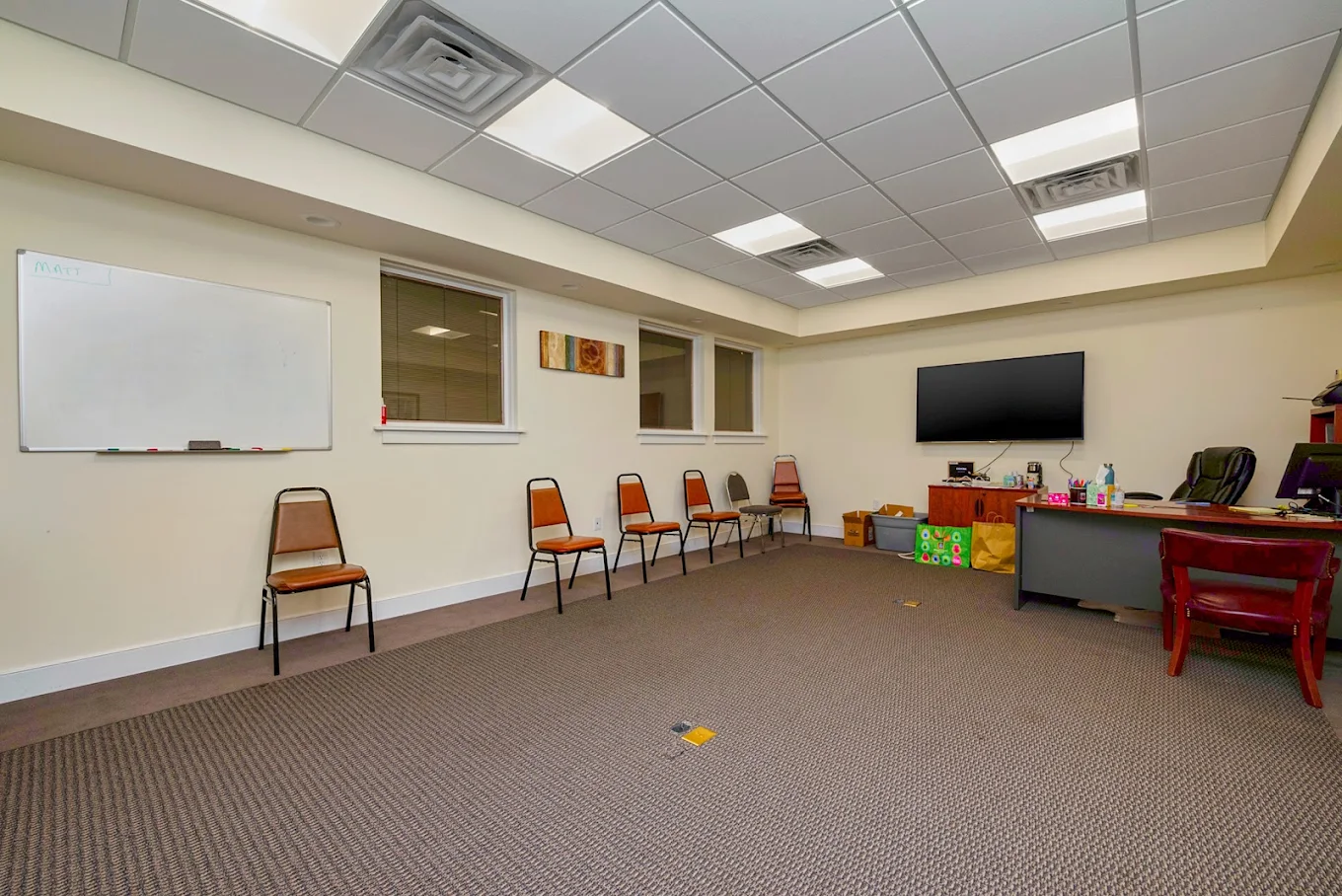 Group therapy room with chairs, whiteboard, and television
