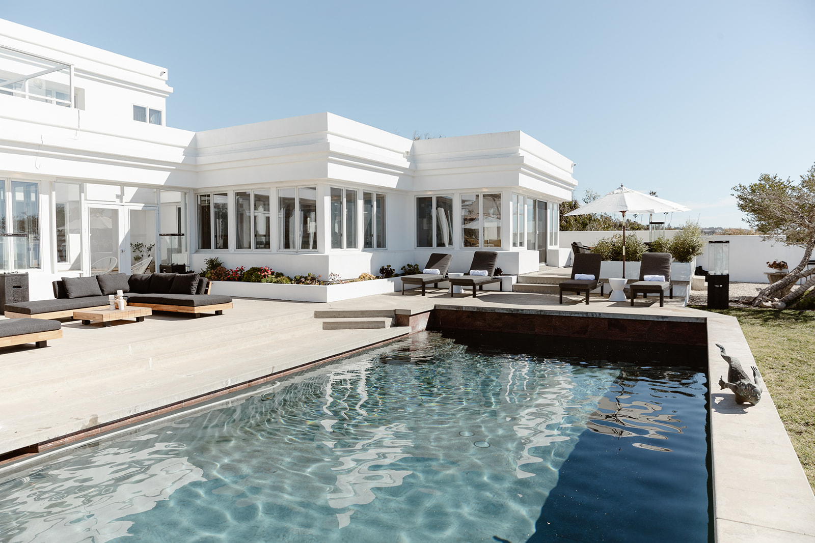  Modern poolside patio with black lounge chairs and ocean views.