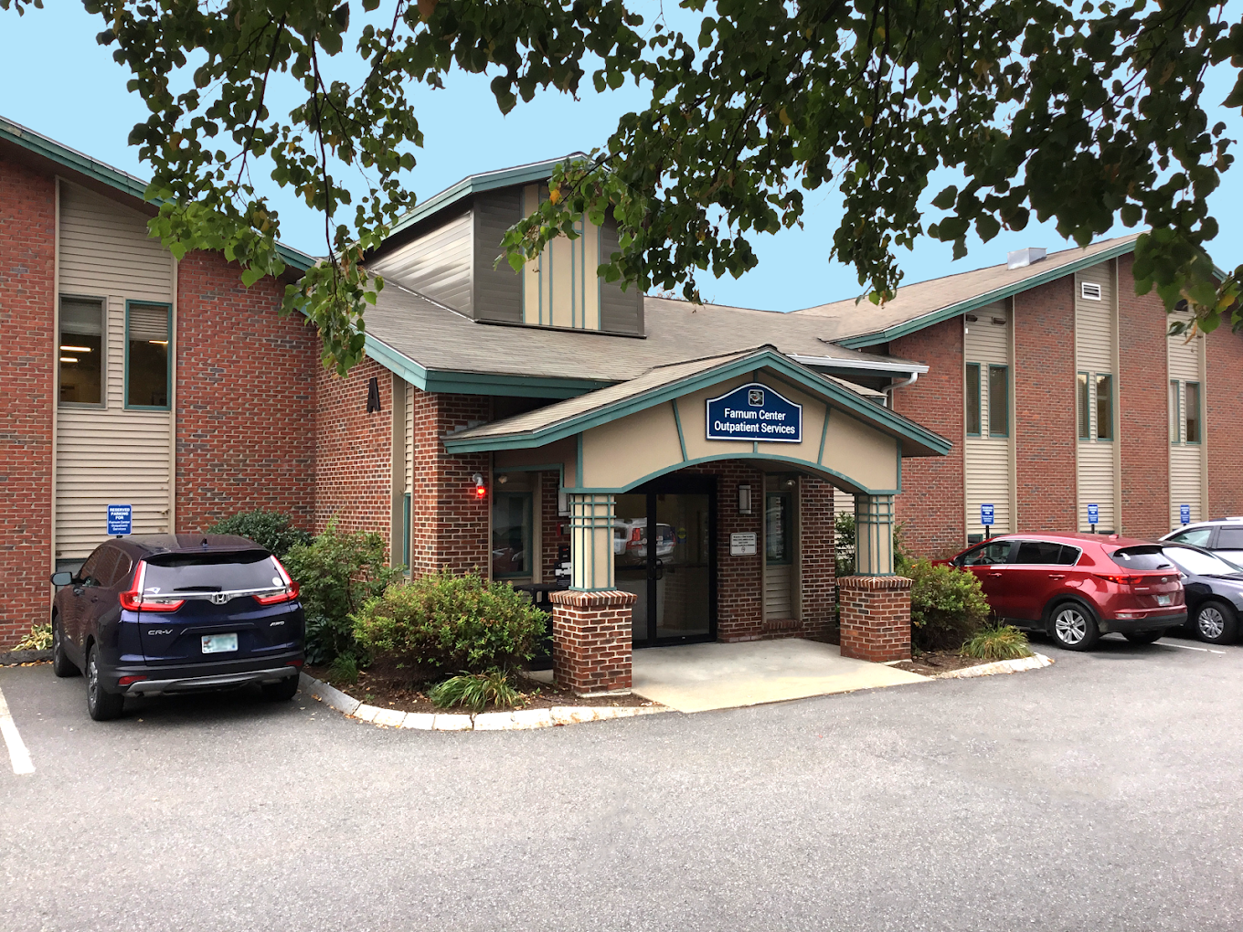Brick building with cars parked in front near main entry