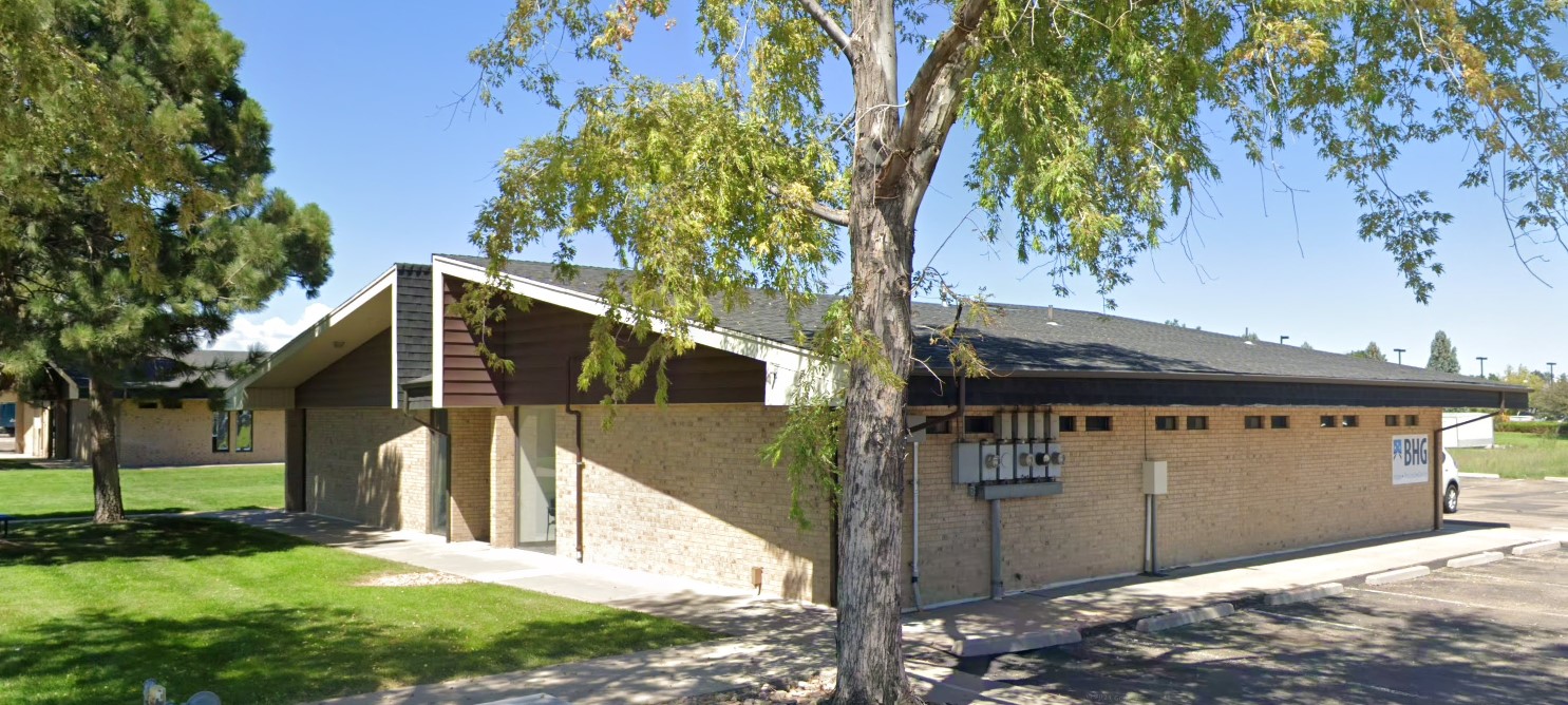 Side entrance of brick treatment center shaded by large tree
