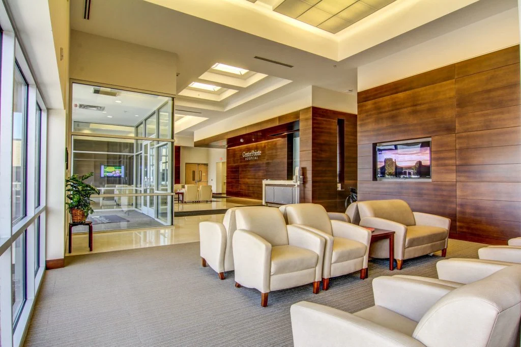 Bright hospital waiting area with armchairs and large windows.
