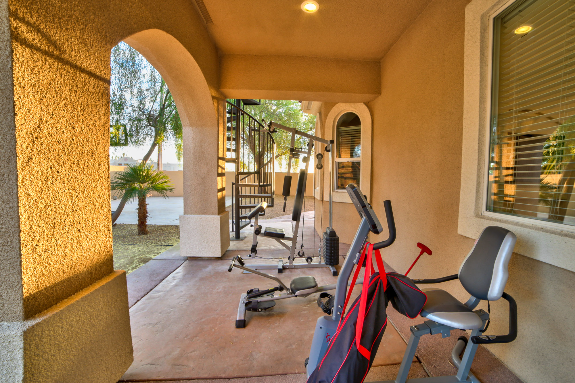 Gym area with fitness equipment under a covered patio.