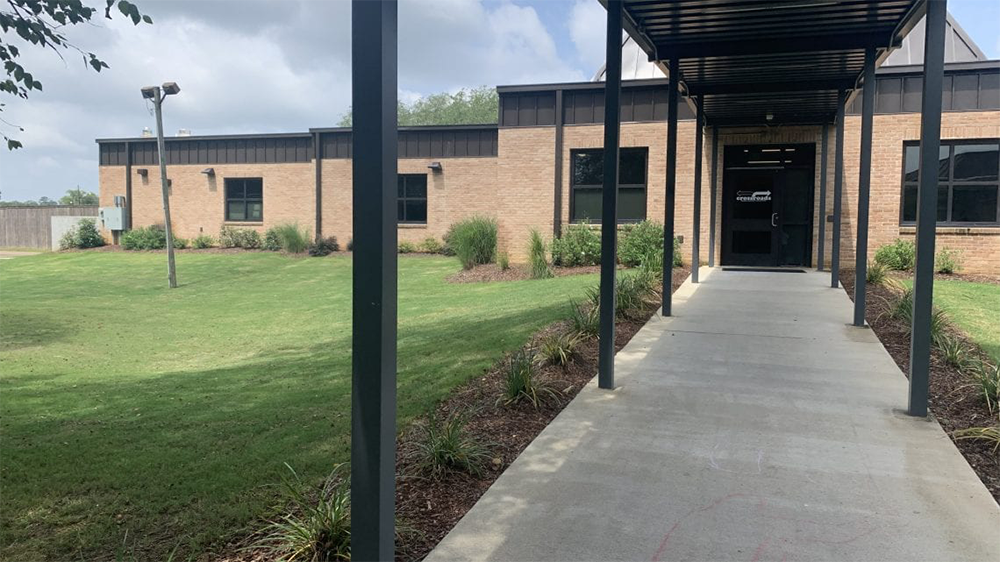 Covered walkway leading to facility entrance beside lawn