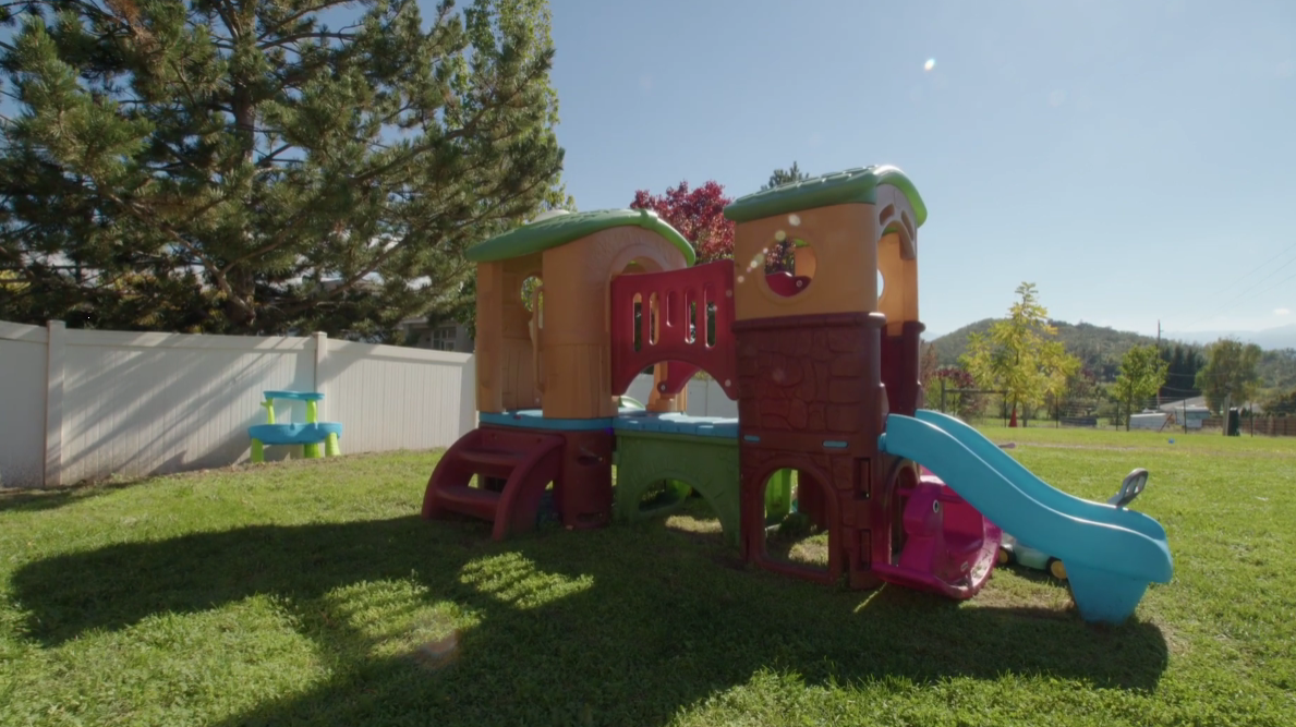 Outdoor play area with slides and climbing structures on grass
