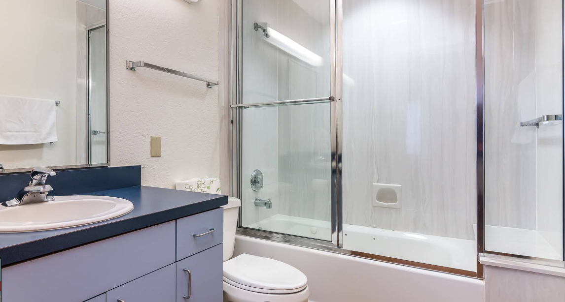 Clean bathroom with sink, toilet, and glass shower doors