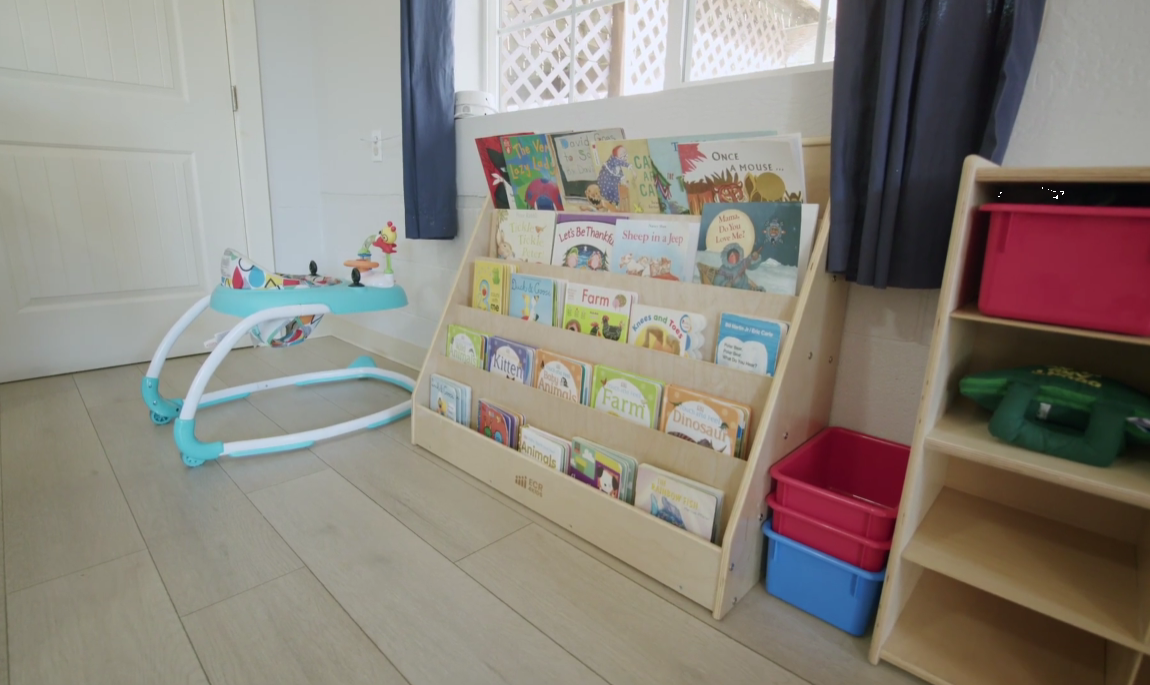 Bookshelf filled with children’s books beside a baby walker
