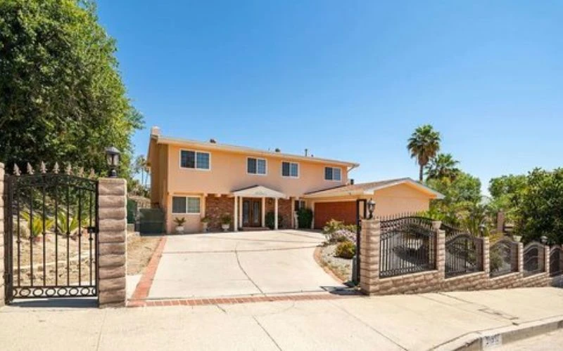 Gated driveway entrance with a peach two-story home