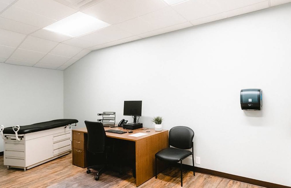 Medical exam room with desk, chair, and exam table