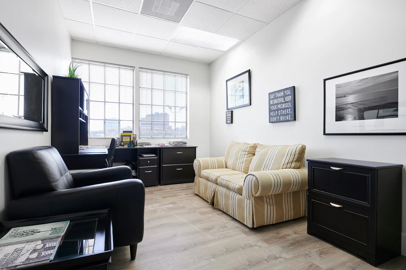 Comfortable counseling office with striped couch, black chairs, desk setup, and motivational wall art