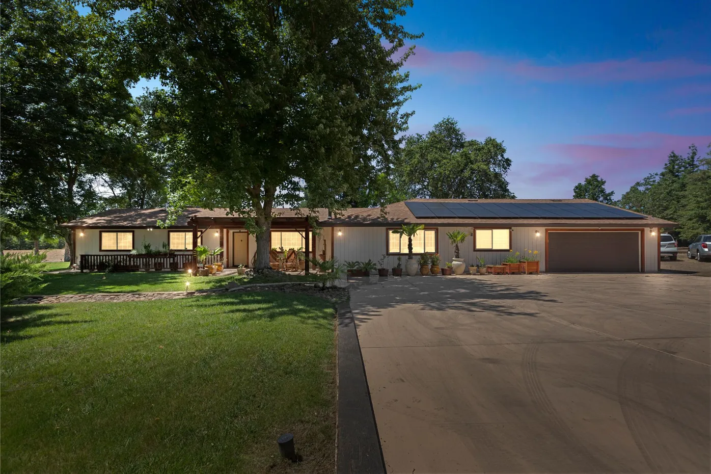 One-story home with lights and solar panels at dusk