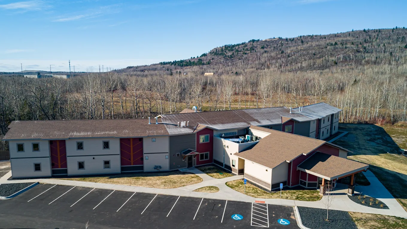 Rehab facility surrounded by trees and hills under blue sky
