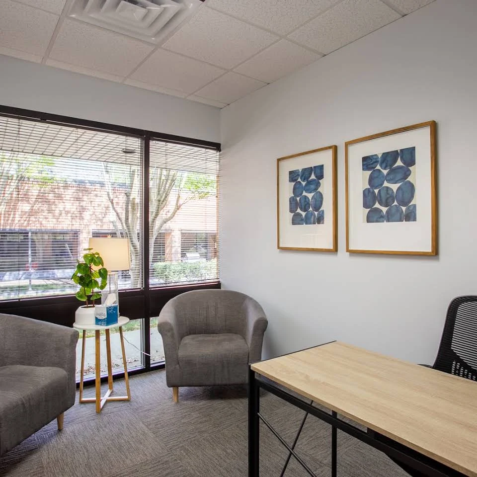 Counseling office with desk, armchairs, window, and wall art