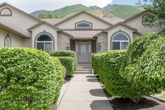 Facility exterior with trimmed hedges and mountains