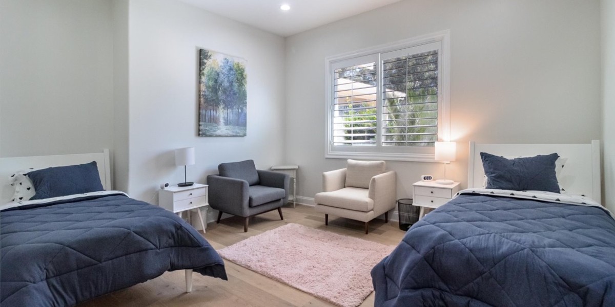 Bright bedroom with twin beds, blue bedding, and a lounge chair