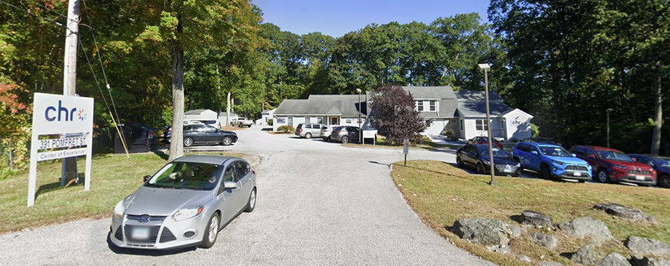 Driveway leading to CHR facility with parked cars and wooded surroundings