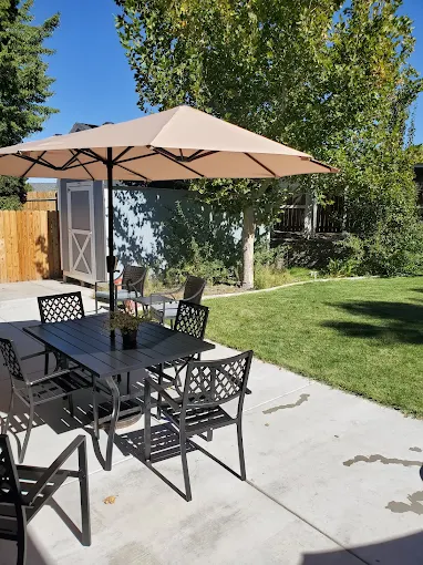 Patio area with umbrella table, chairs, and green backyard