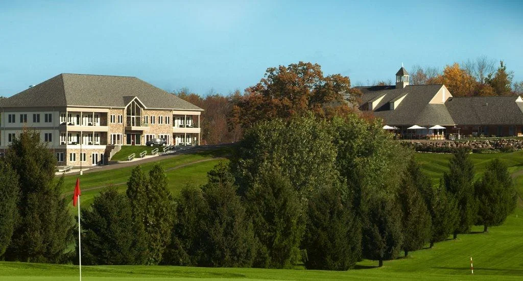 Large facility buildings on landscaped grounds with trees.