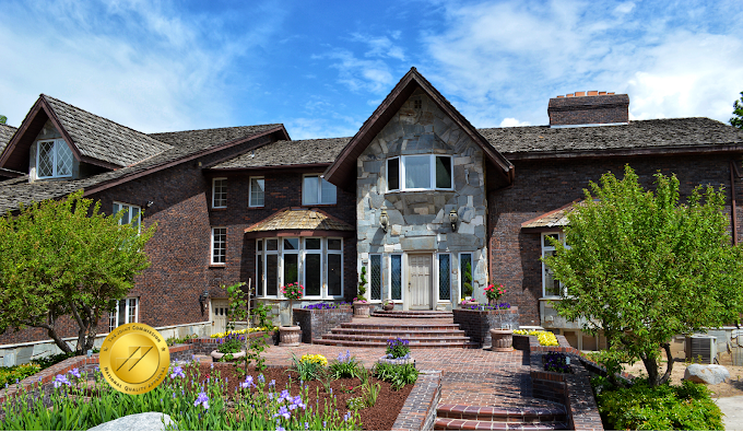 Brick estate with stone entry and manicured flower beds