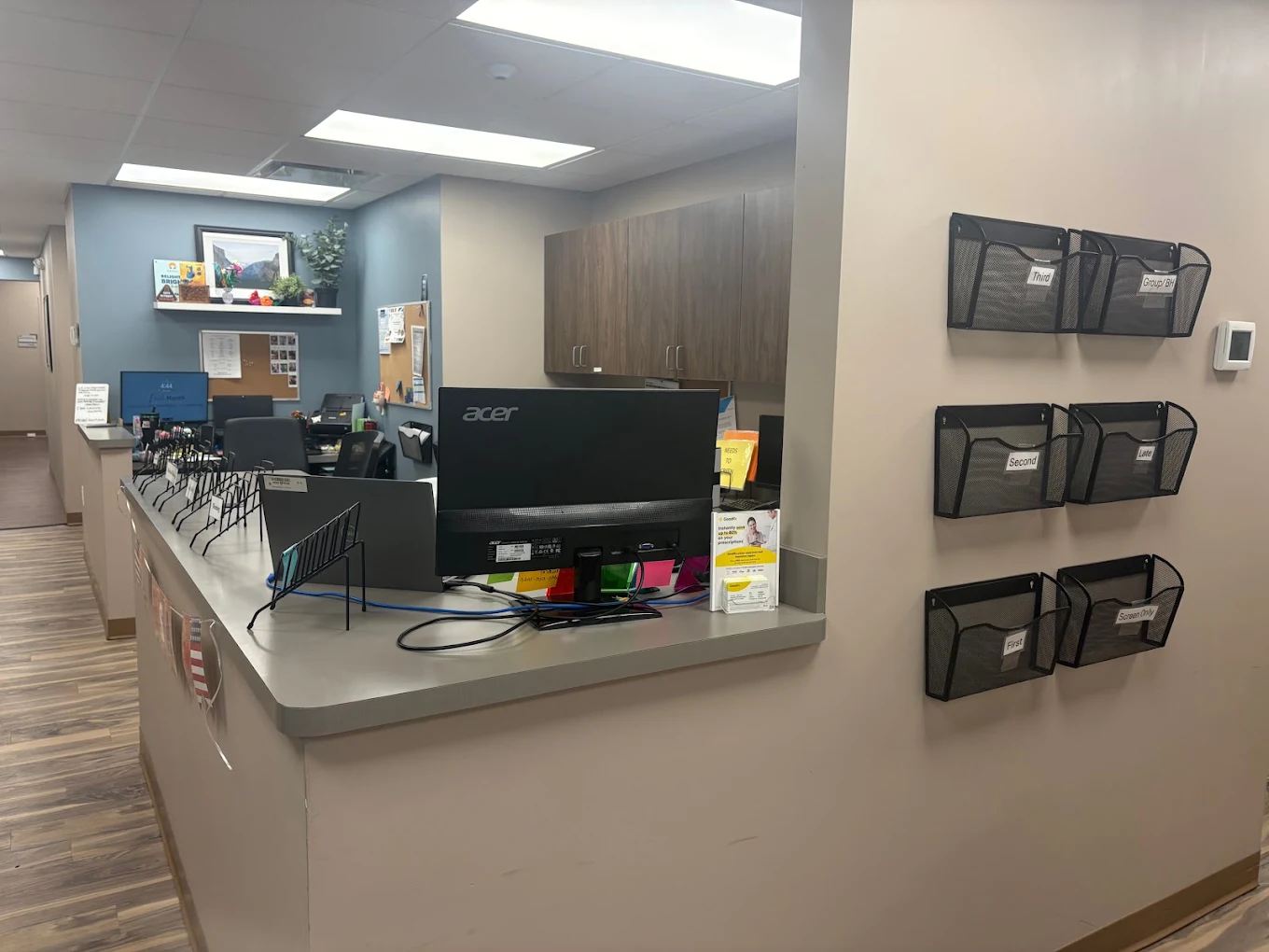 BrightView Akron reception desk with computer workstations, wall-mounted document organizers, cabinets, and hallway