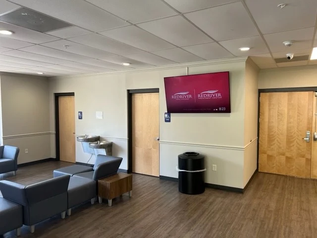 Lobby seating area at Red River Treatment Center with chairs, wall-mounted display, water fountains, and interior doors