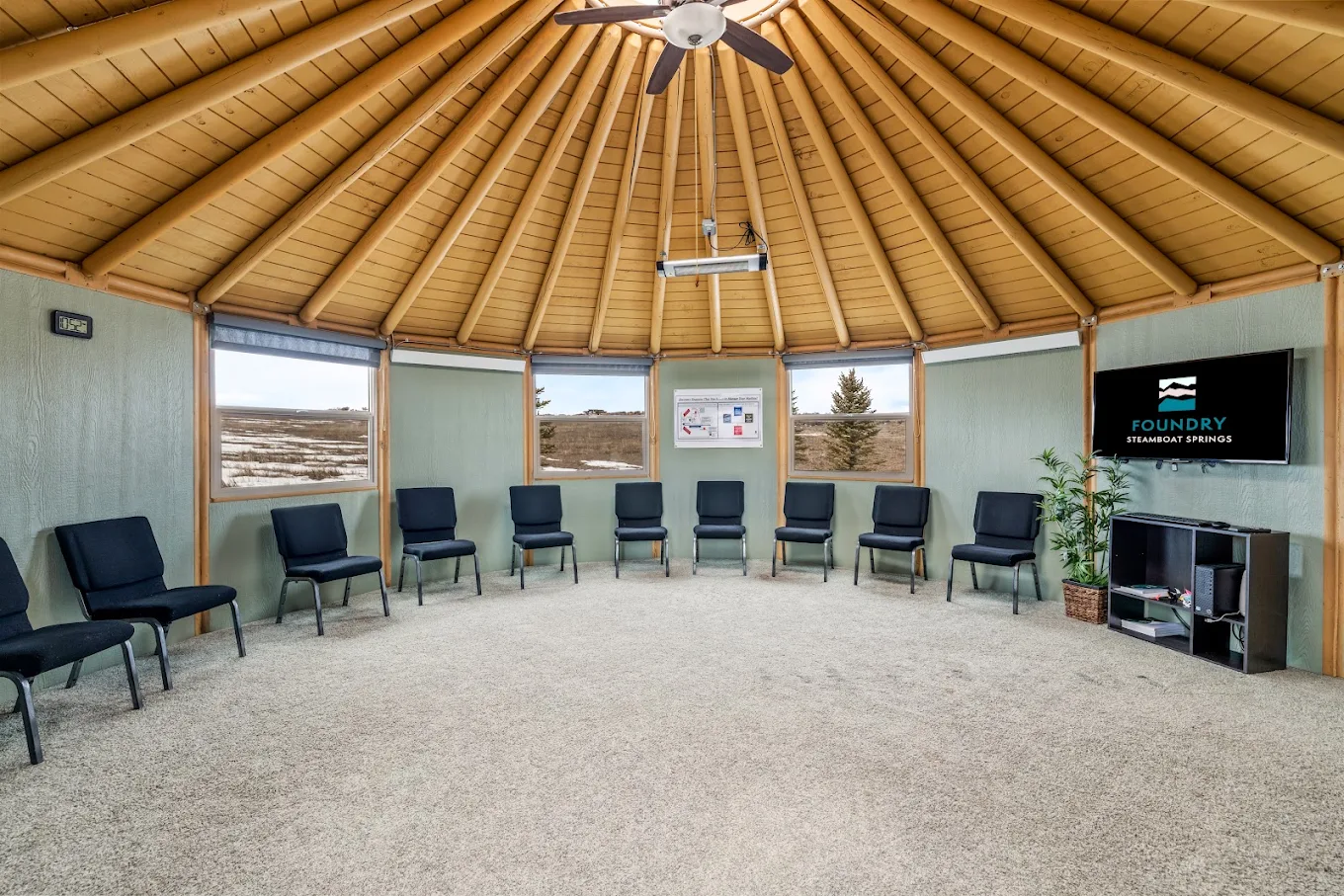 Circular group therapy space with chairs arranged around an open floor beneath a vaulted wood ceiling